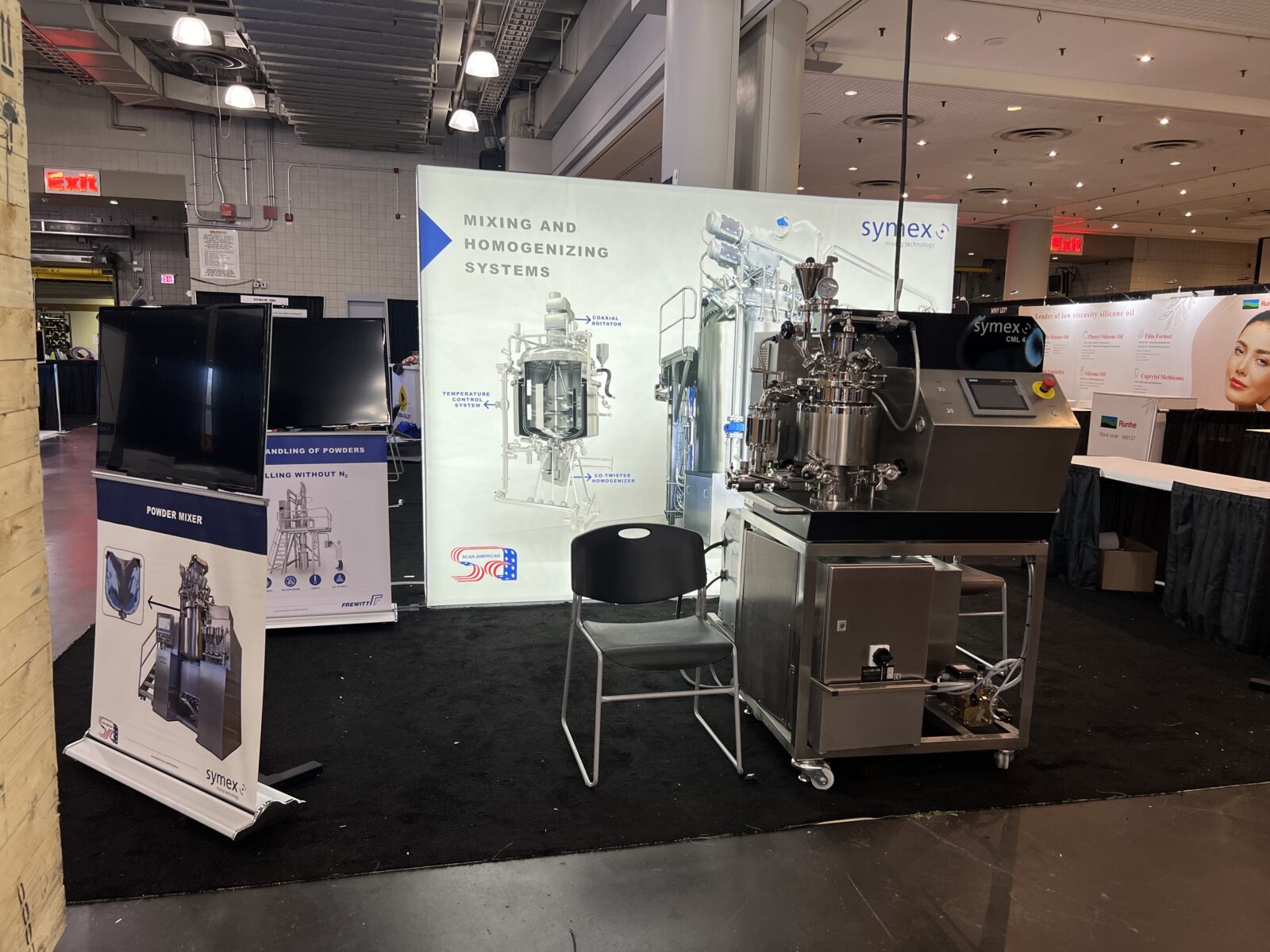 Symex booth display at INTERPHEX 2024 featuring a powder mixer and a CML 4 machine.
