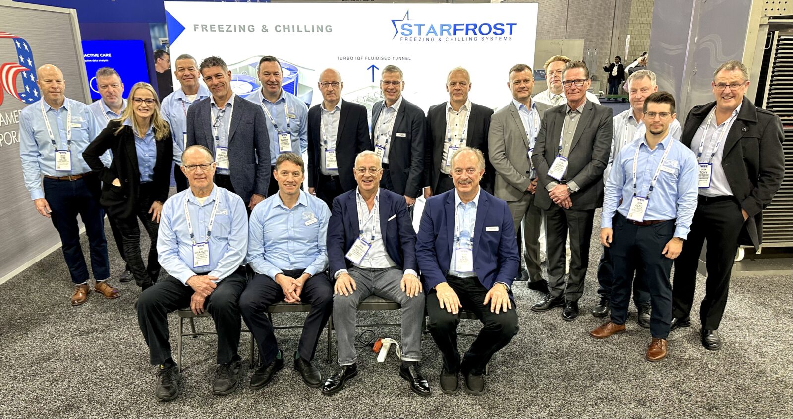 Edited group photo of Scan American employees and international partners standing together at the IPPE 2024 booth, taken from eye level.